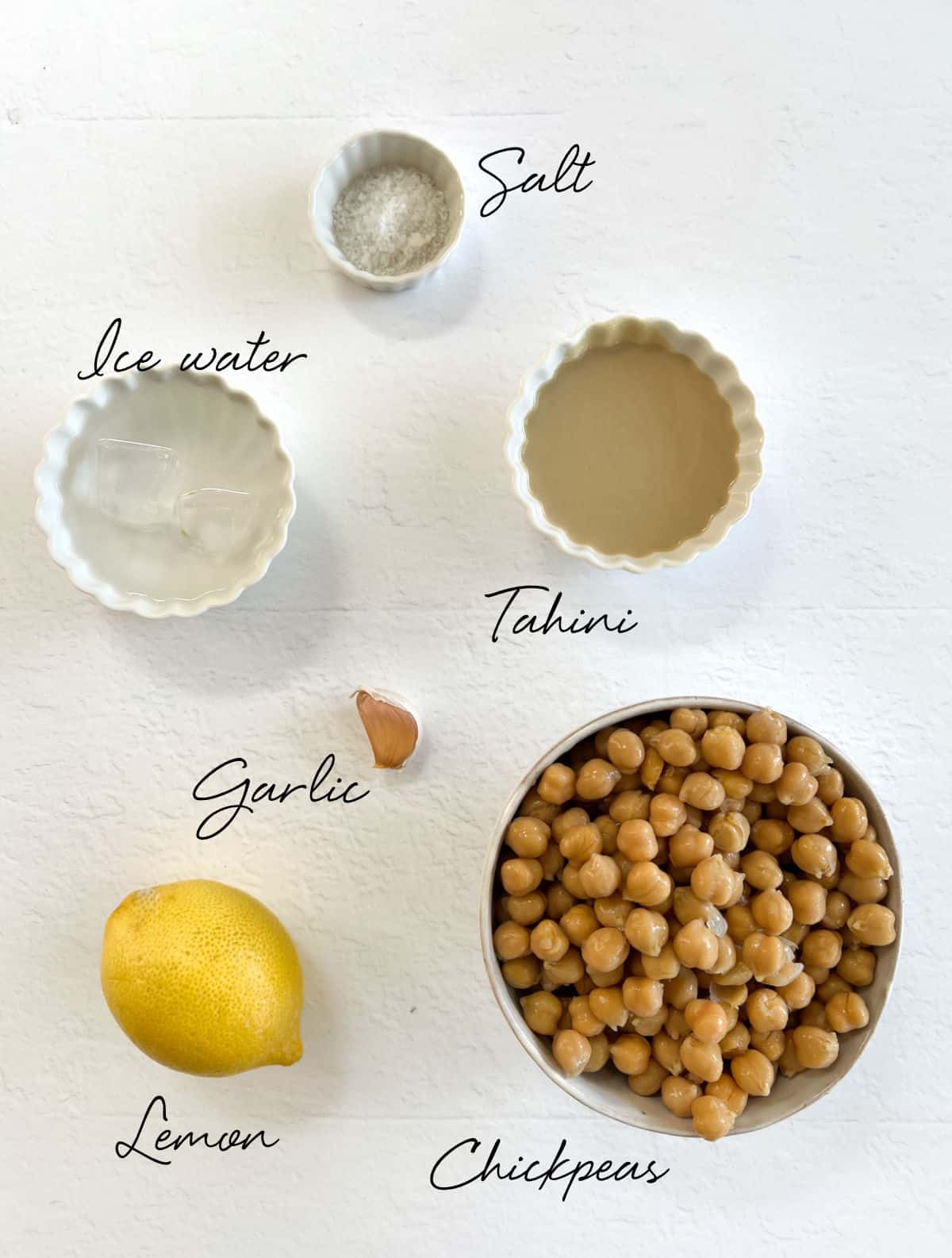 salt, tahini, chickpeas, water, lemon and a clove of garlic laid out in bowls