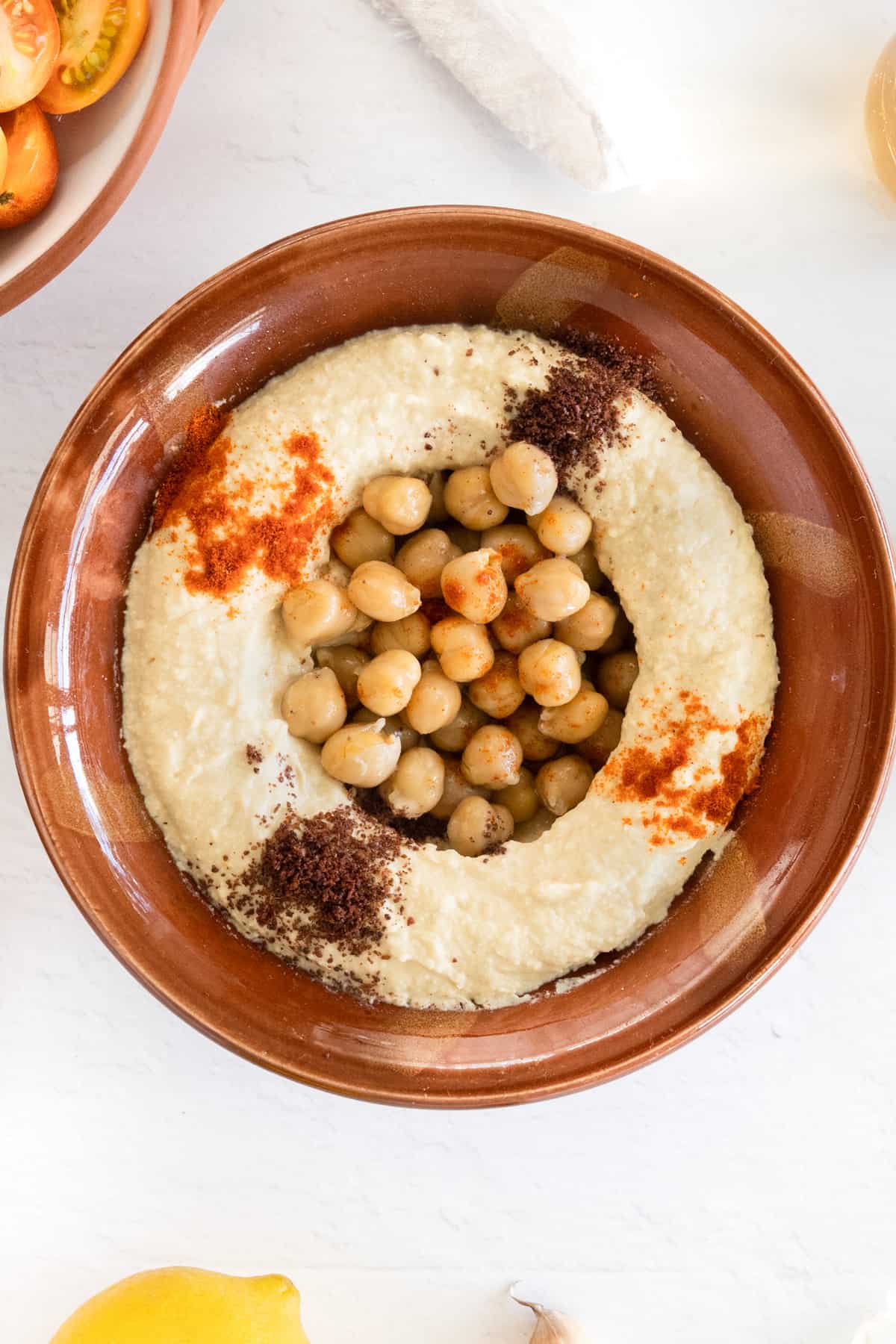 a brown clay bowl filled with blended chickpeas topped with whole cooked chickpeas