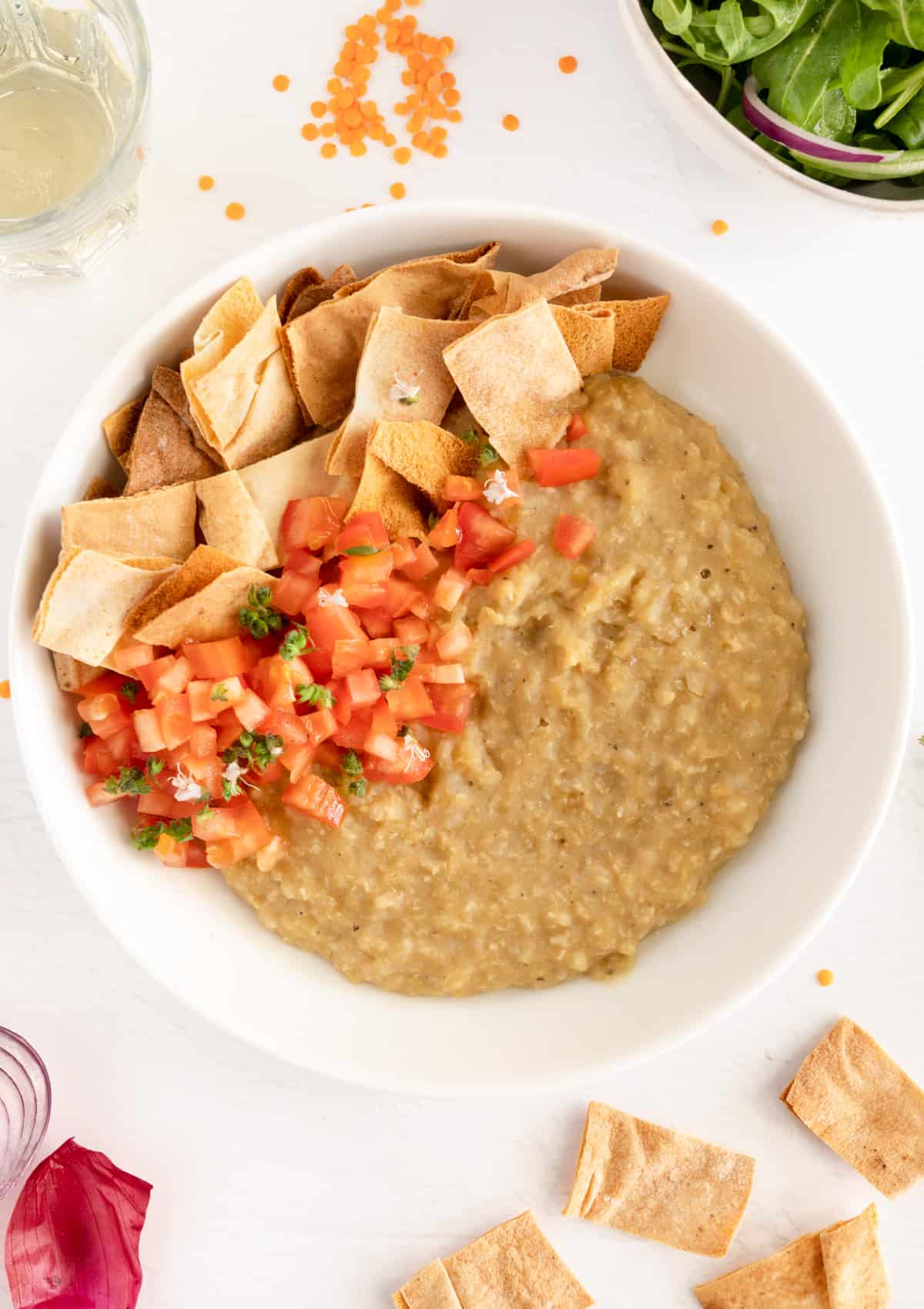 a round plate filled with thick yellow porridge and browned Lebanese pita pieces