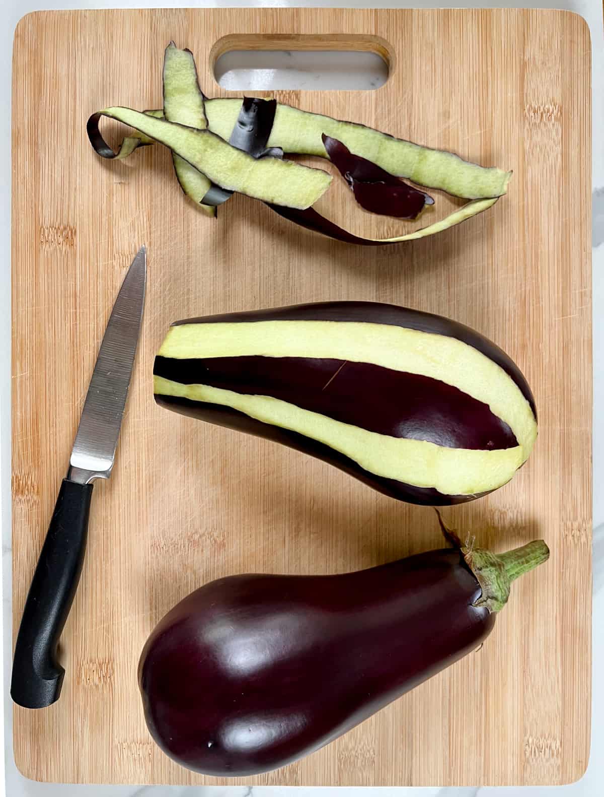 two globe eggplants one partially peeled