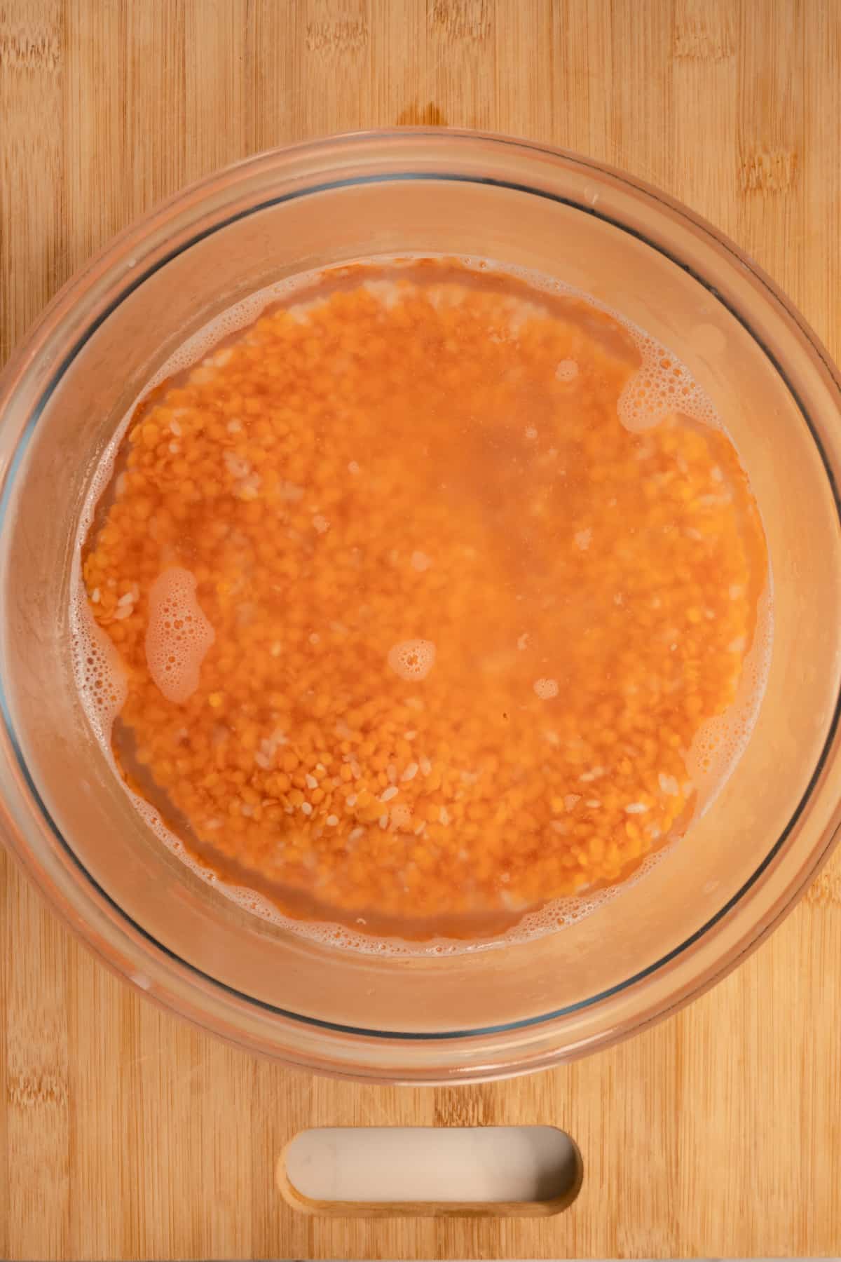 red lentils soaking in water in a glass bowl