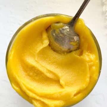 a bowl filled with yellow sorbet and a spoon