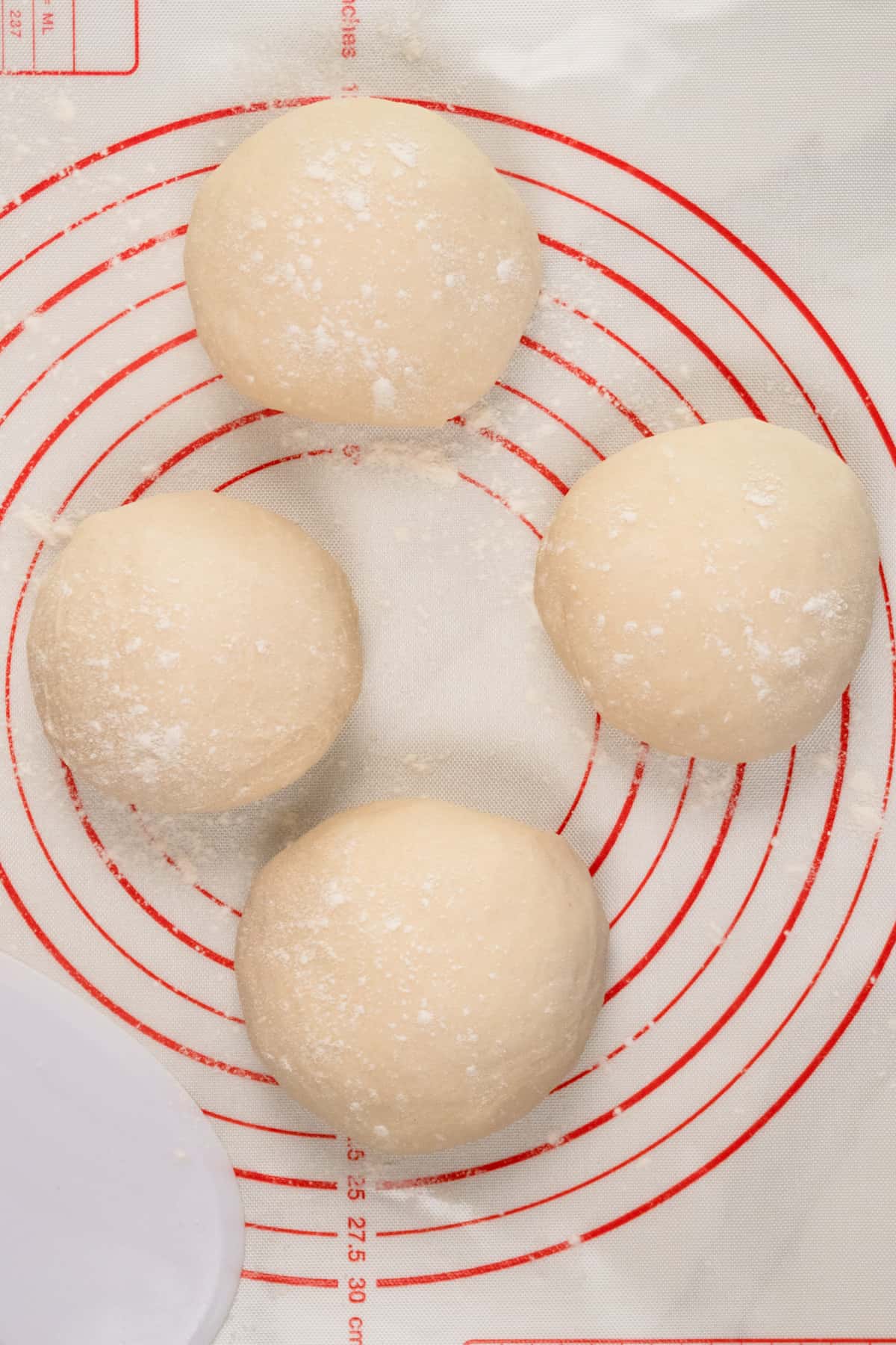 four dough balls on a silicone mat