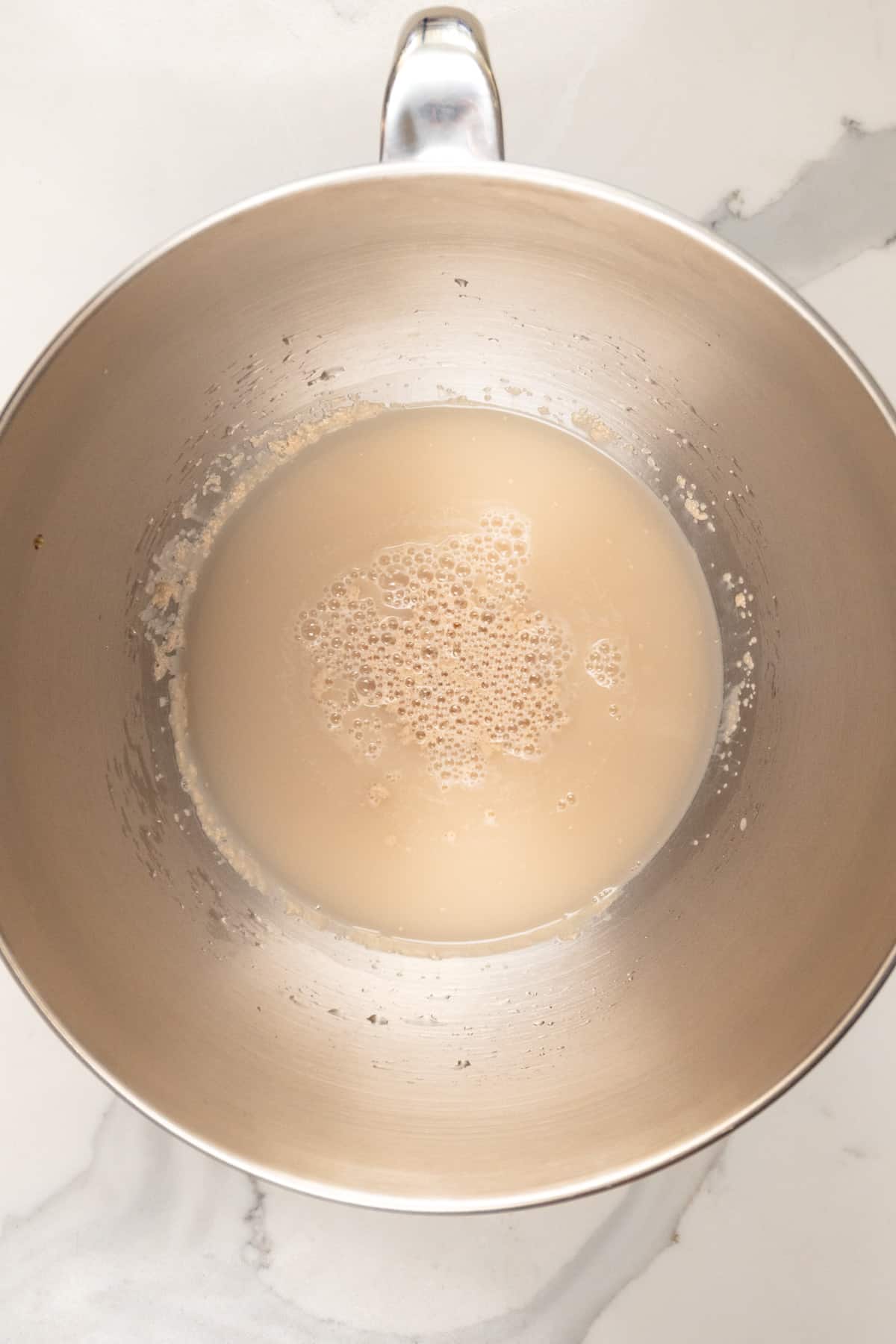 murky water with yeast bubbles in a silver bowl