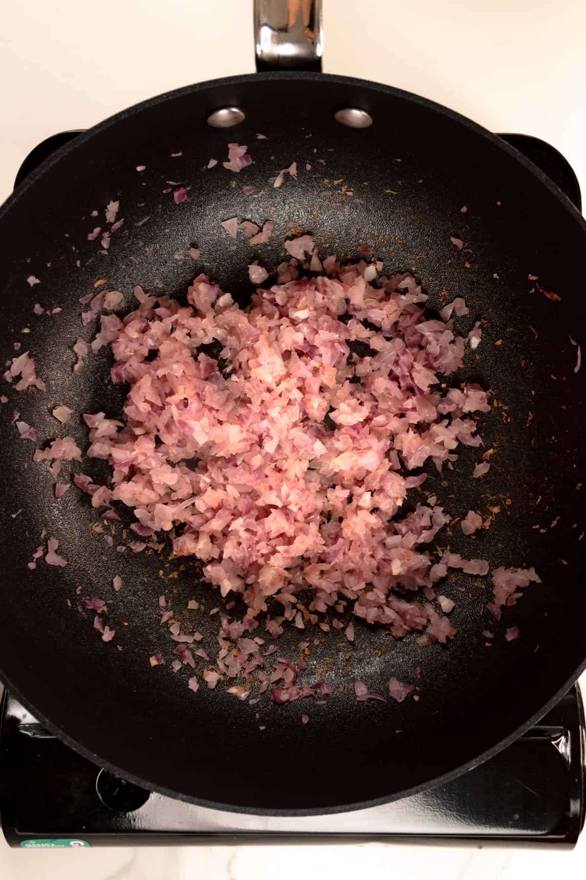slightly brown finely diced red onions in a black pan