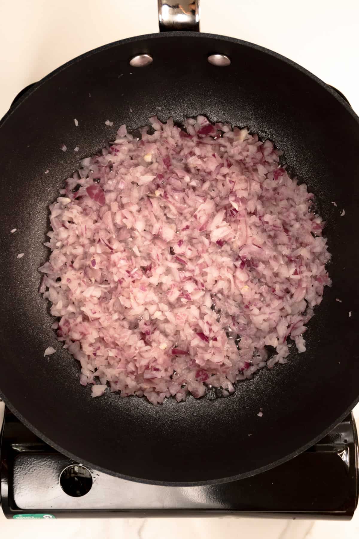 finely diced red onion in a black pan