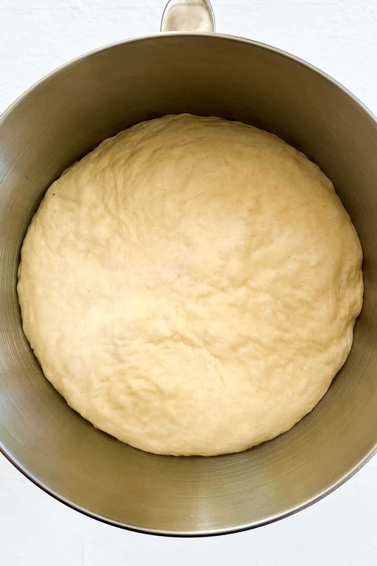 risen dough in a silver bowl