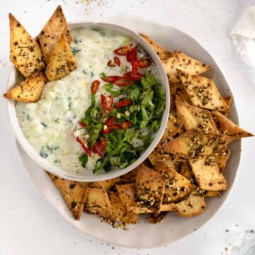 whites bowls of white dip topped with green herbs and golden pita chips