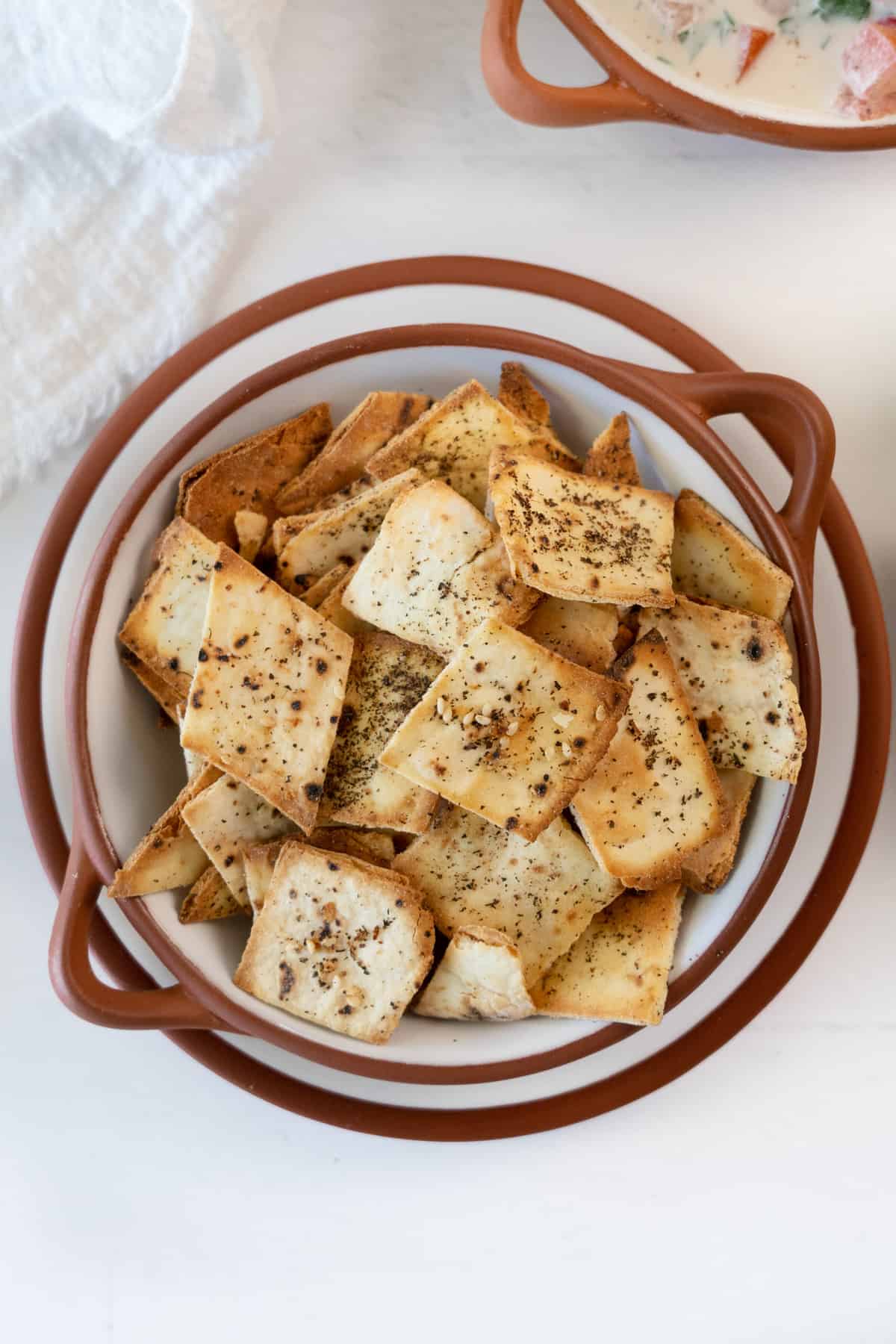 a brown ceramic bowl with golden pita chips