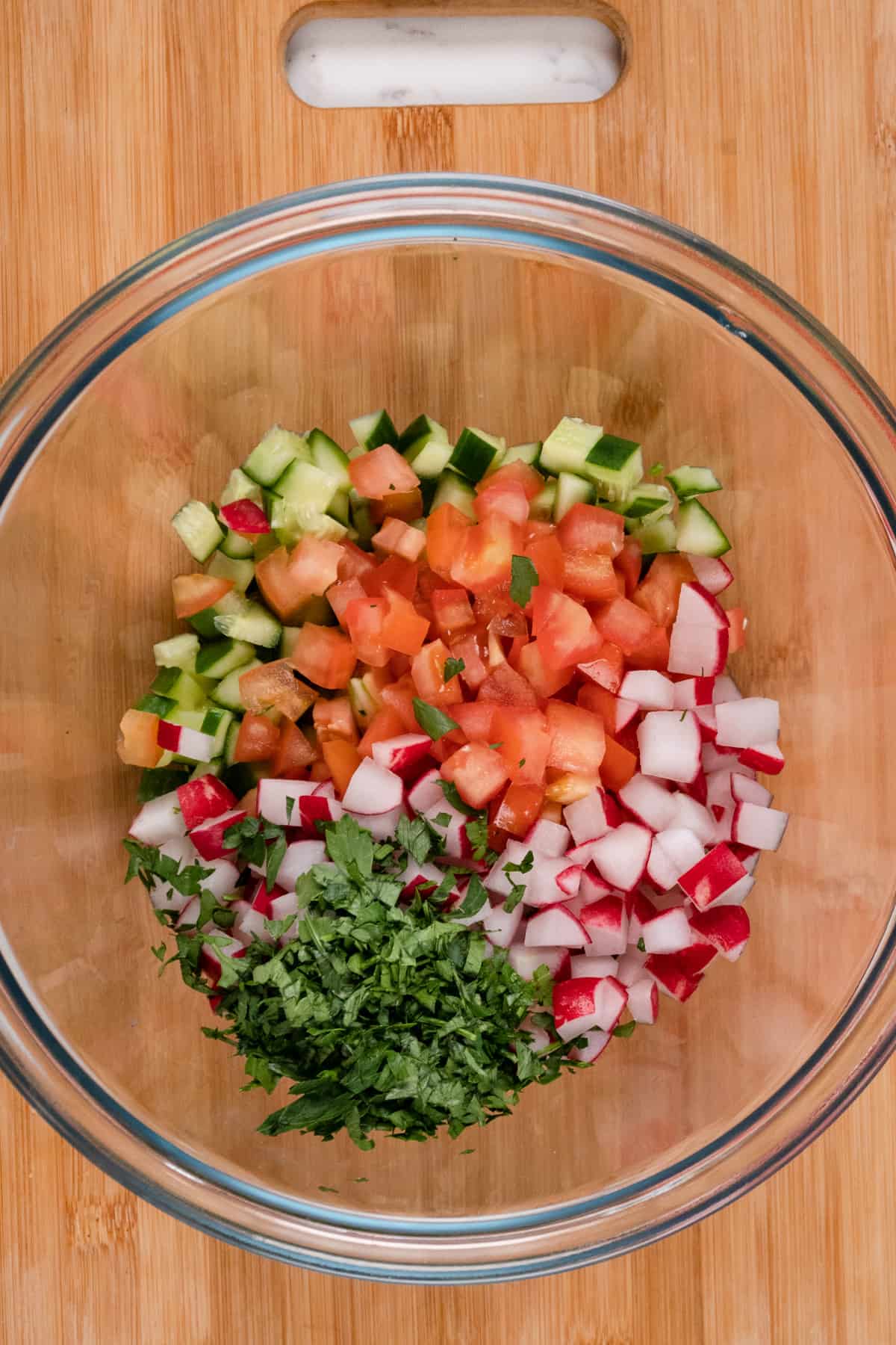 diced tomato, radish, parsley and cucumber in a bowl