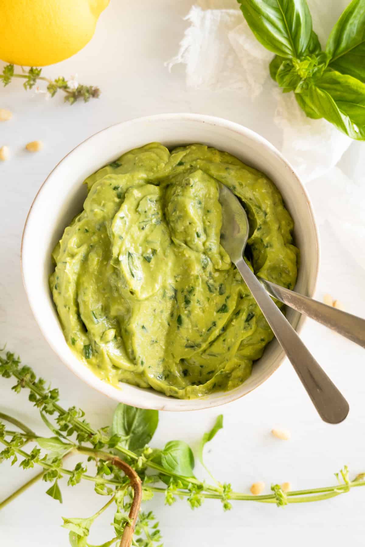 two spoons in a bowl of thick green herb sauce