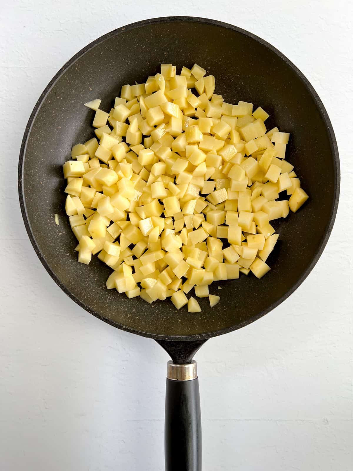uncooked cubed potatoes in a black fry pan