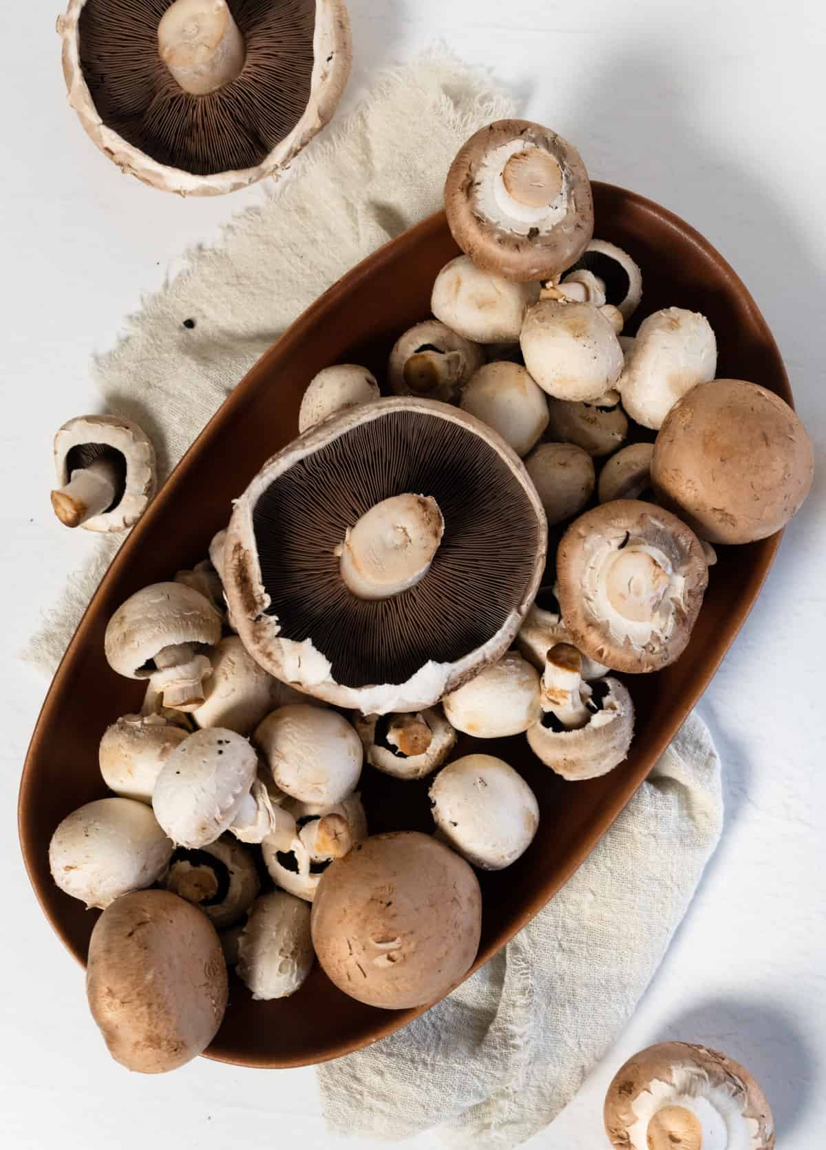 a brown plate filled with different sized round mushrooms