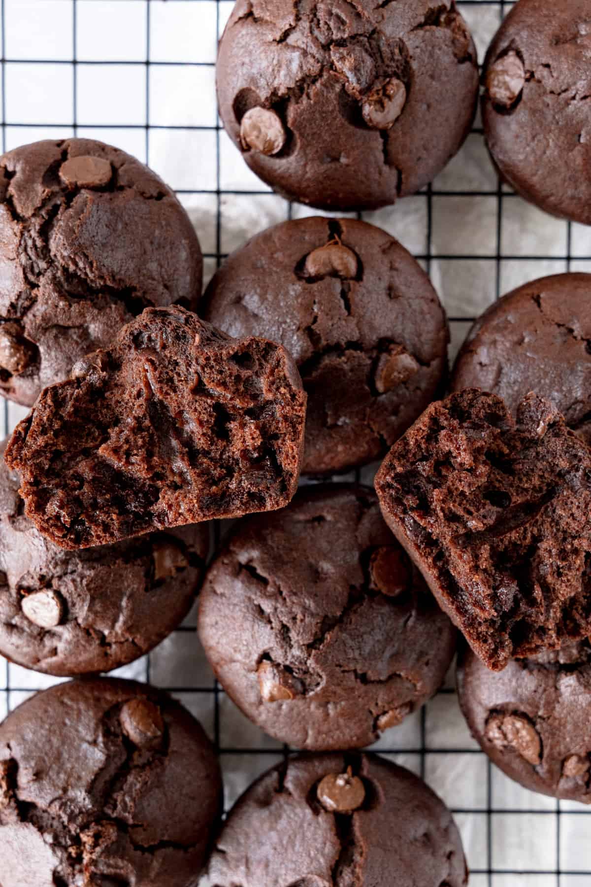 a stack of chocolate muffins with one torn in half showing the insides