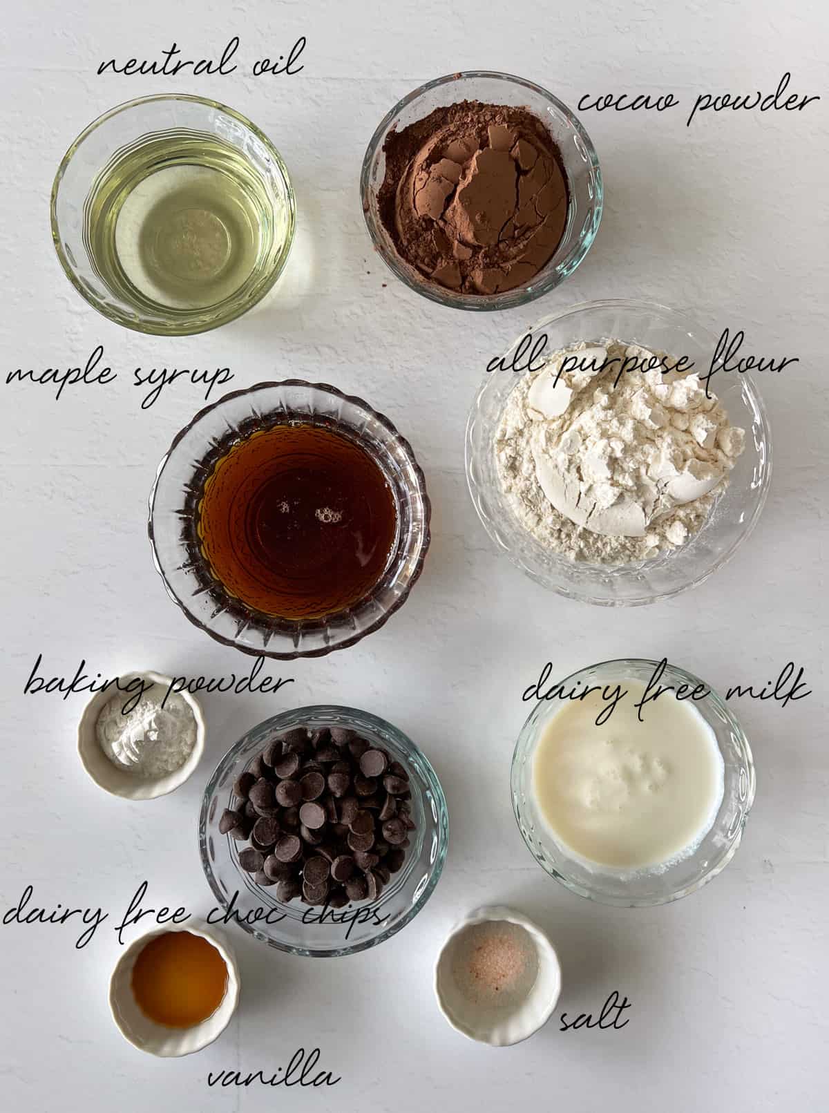maple syrup, oil, flour, cocao, choc chips, milk, salt, vanilla, baking powder laid out in bowls