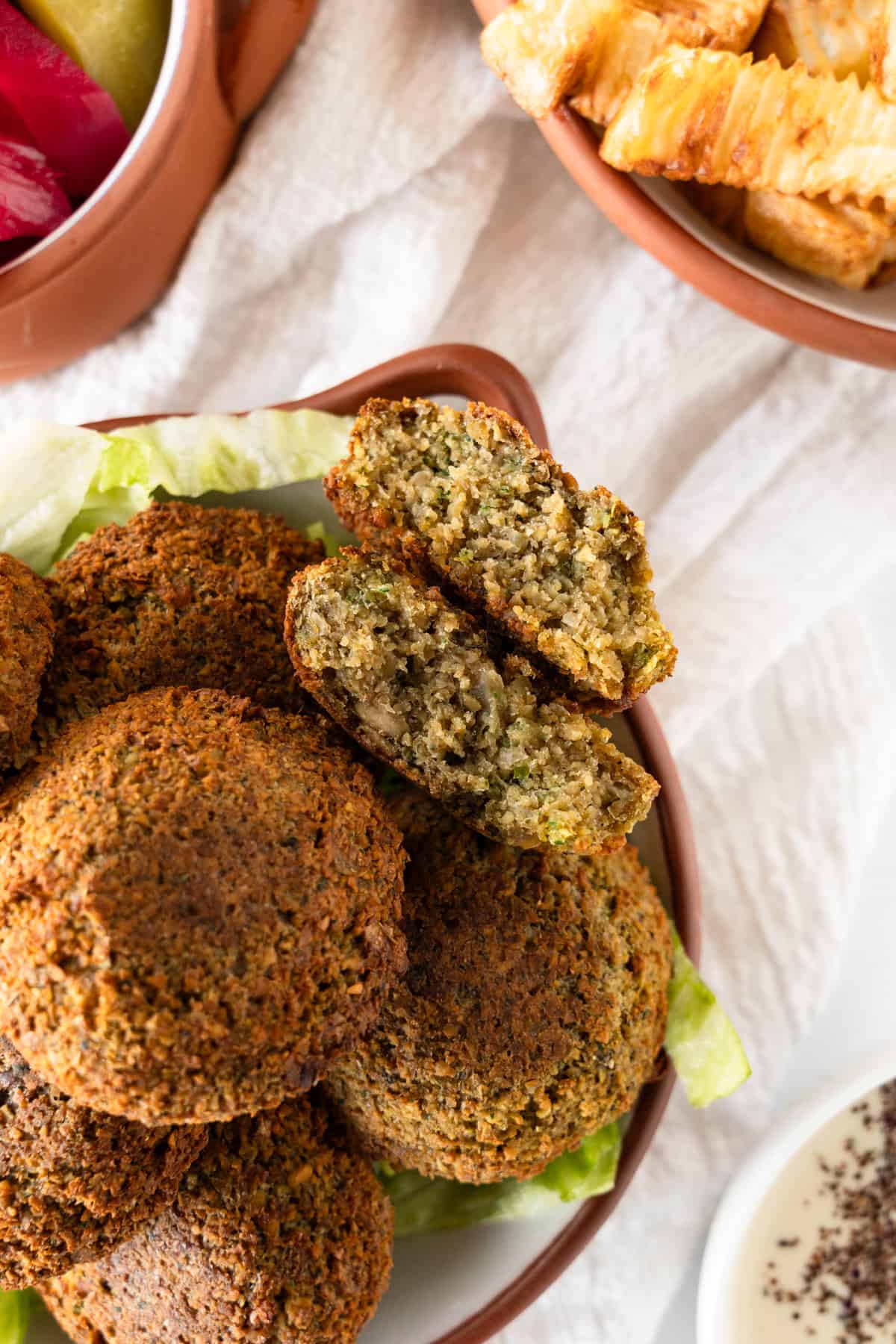 a stack of golden falafels with one halved with its insides showing