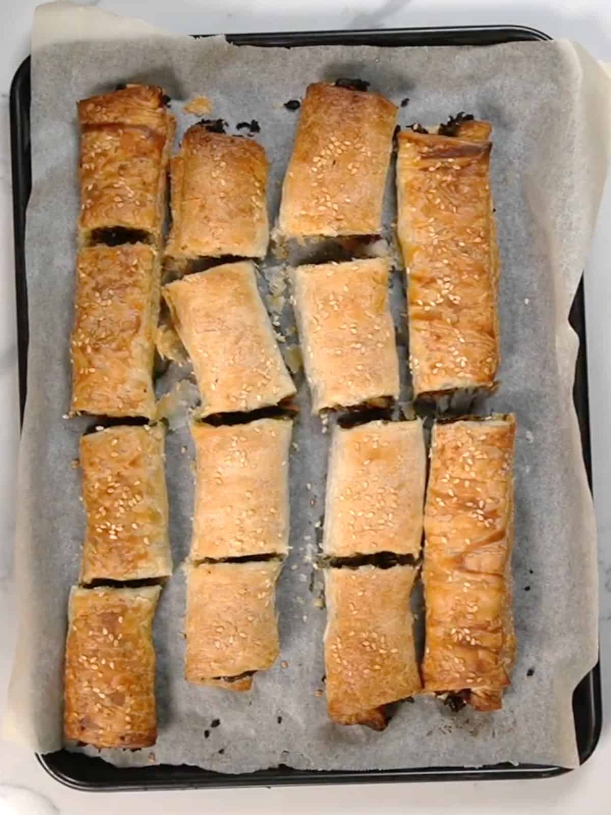 golden flaky puff pastry rolls on a paper lined tray