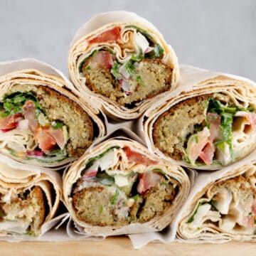 a stack of pita sandwich rolls filled with veggies and falafel