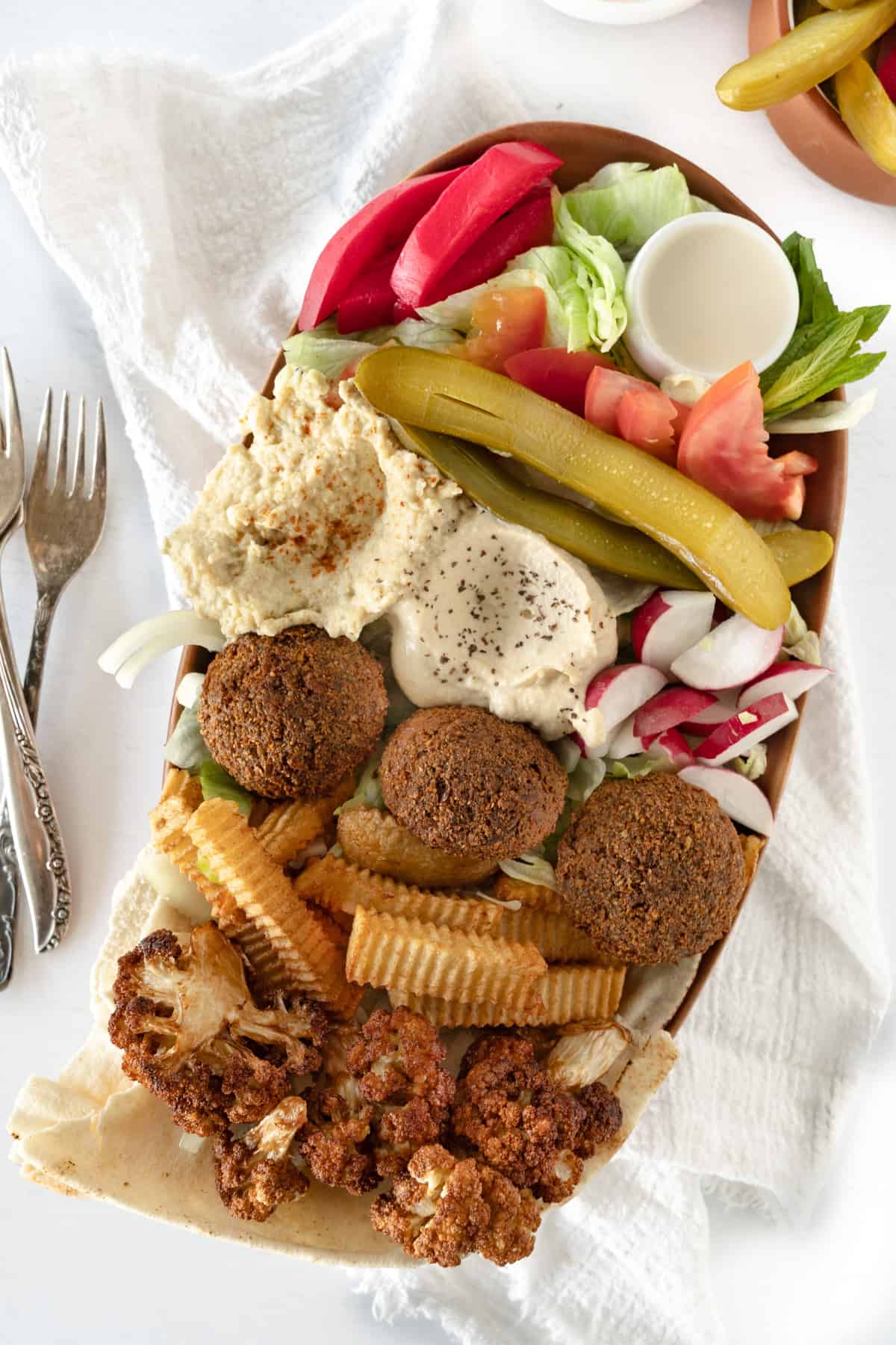 three falafels in a bowl with fresh and cooked veggies