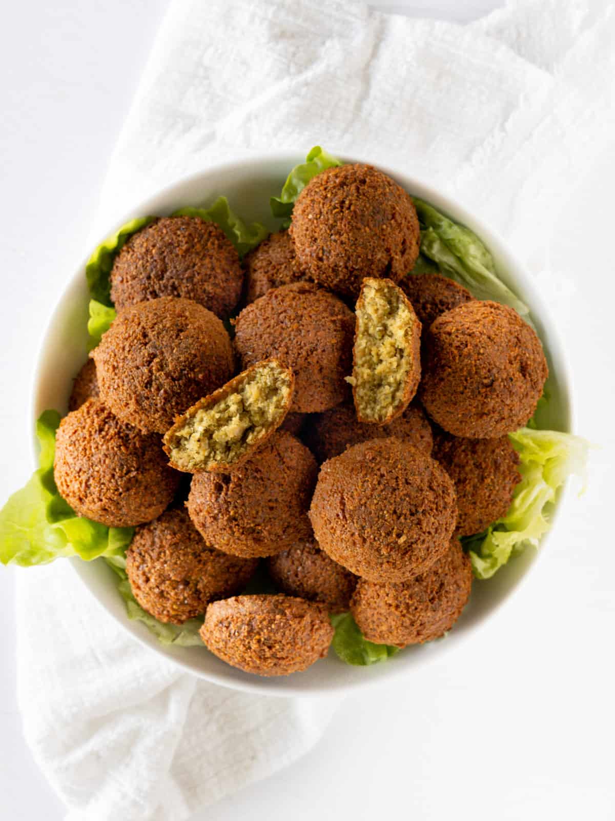 a white round bowl of golden brown falafel balls