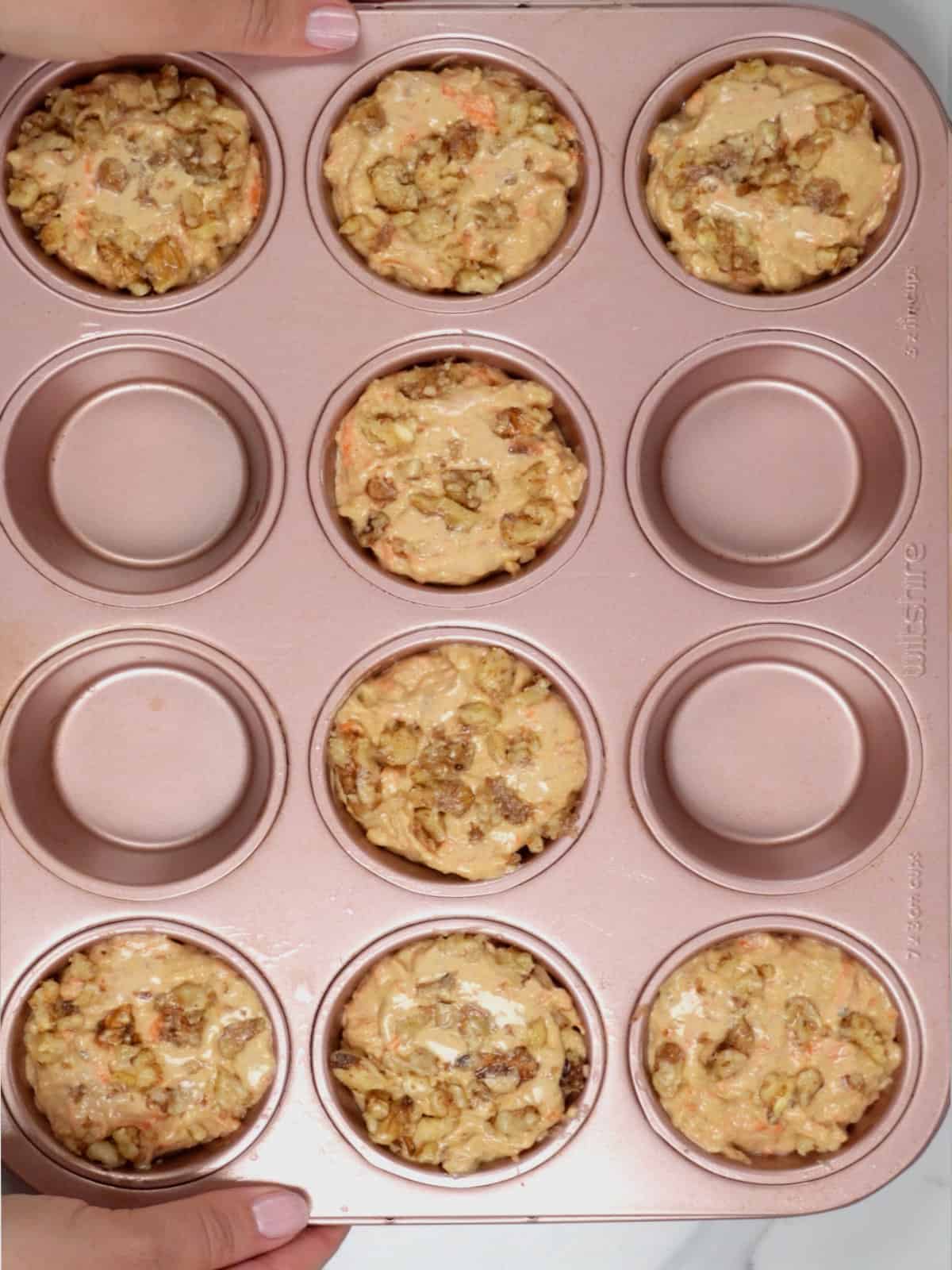 unbaked batter in 8 cups of a pink muffin tray