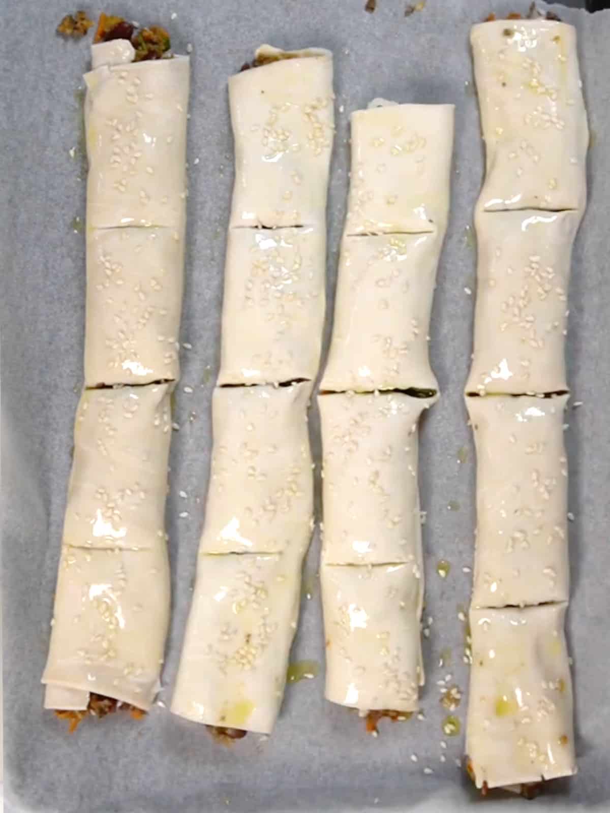 uncooked vegetable sausage rolls on a paper lined tray