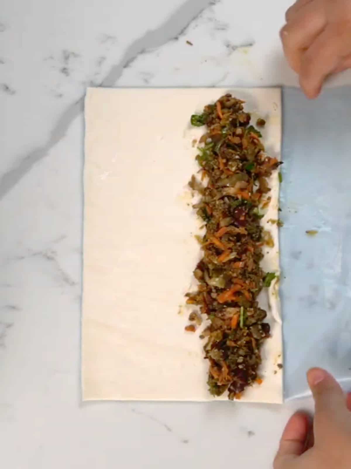 a line of vegetable filling on a sheet of puff pastry dough