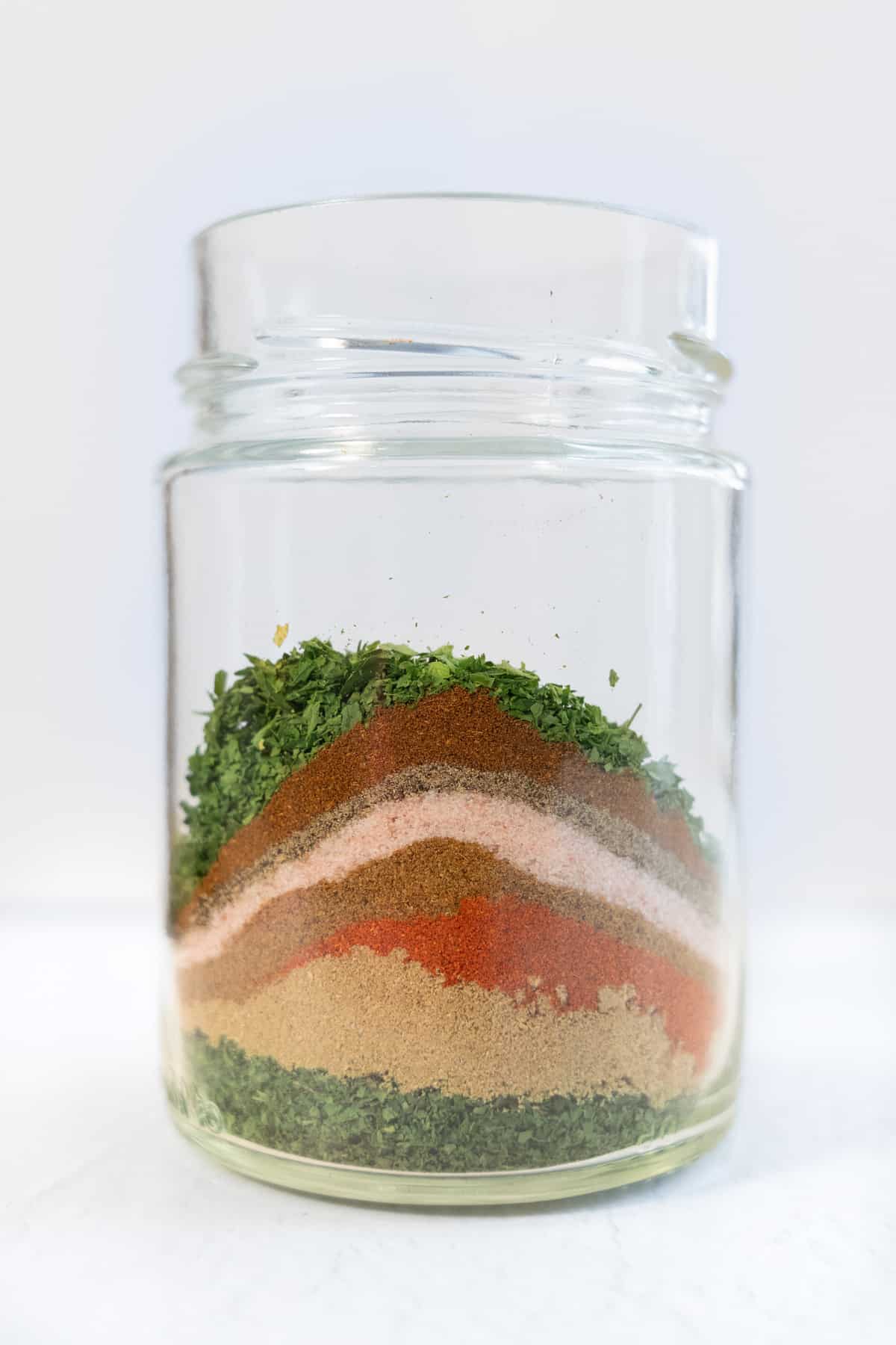 a jar filled with layers of dried herbs and spices for falafel