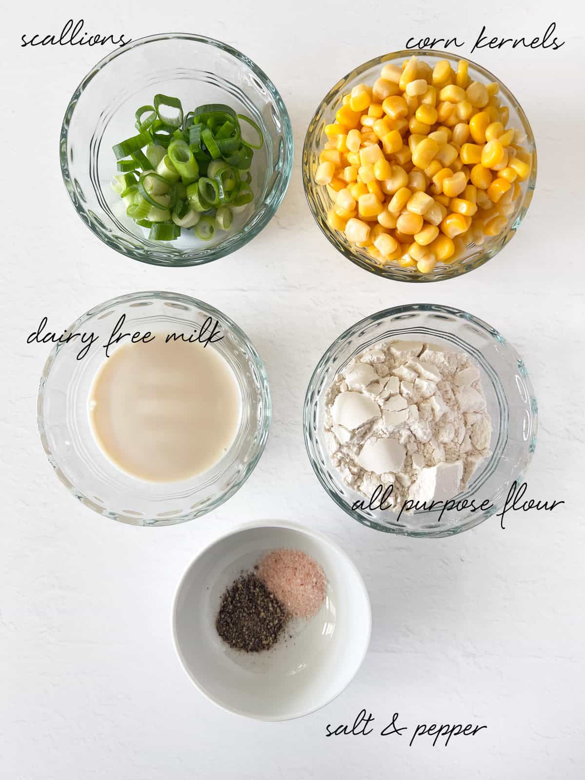 five bowls with corn kernels, slices scallions, milk, flour, salt and pepper
