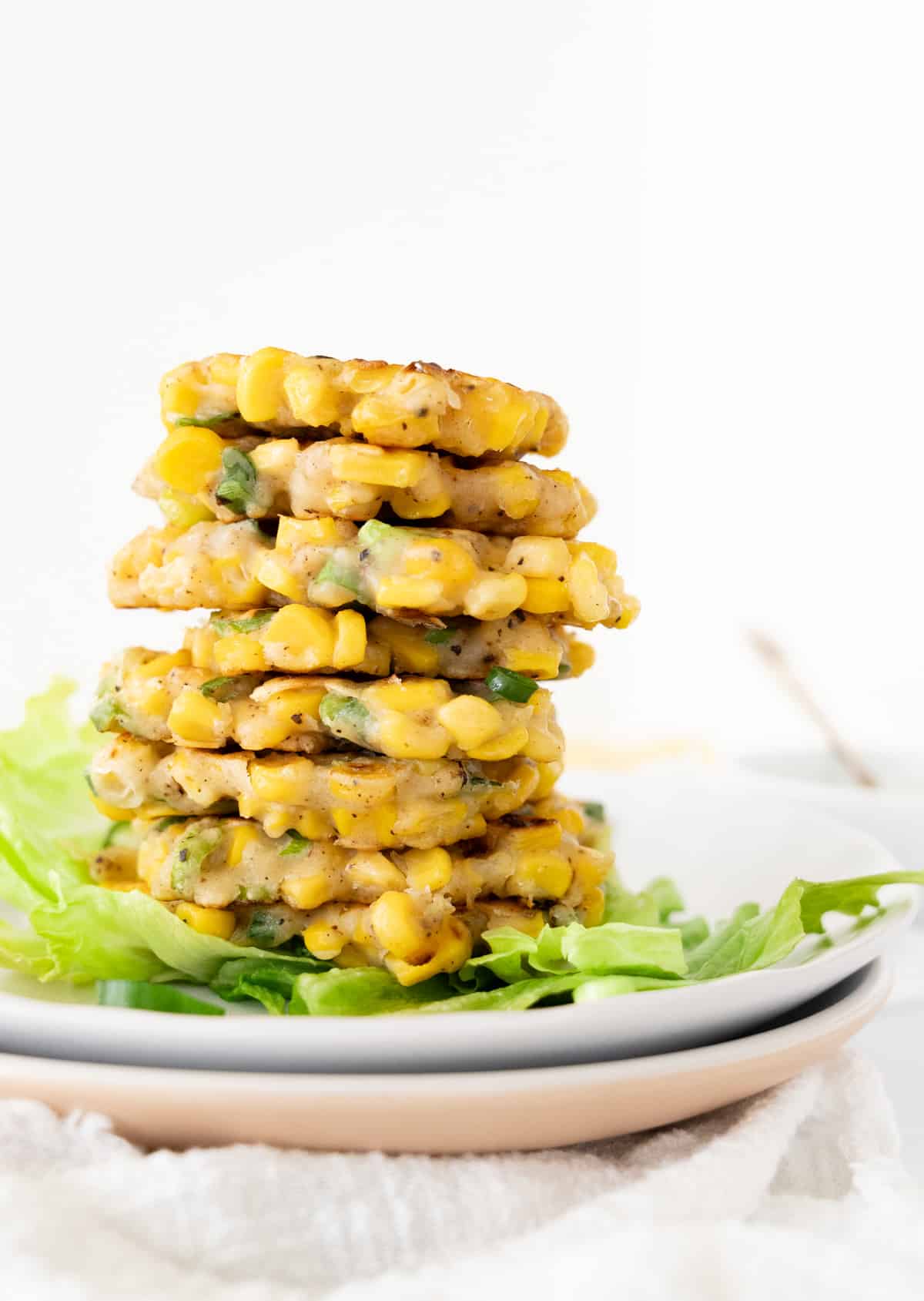 a stack of corn fritters on two plates with green lettuce
