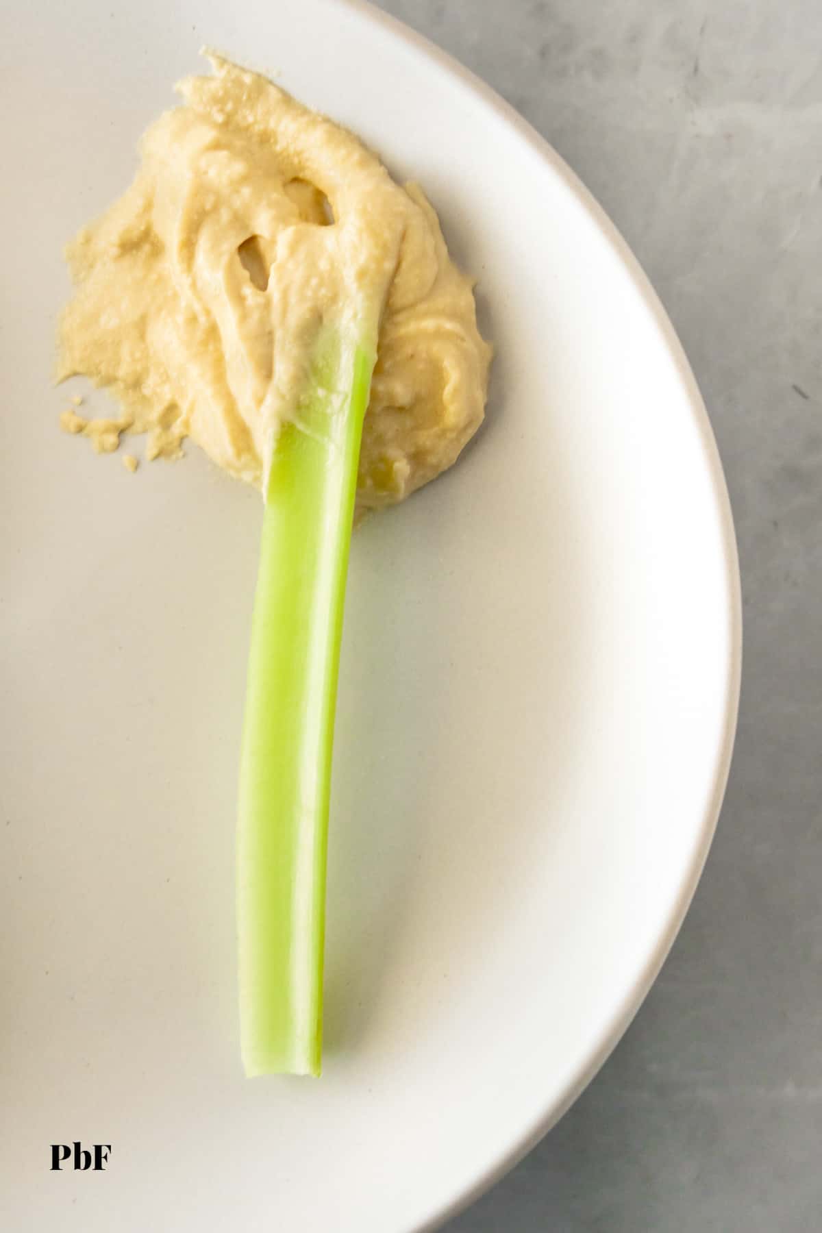 a celery stick with hummus on it