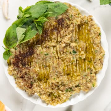 a white plate filled with eggplant dip garnished with mint