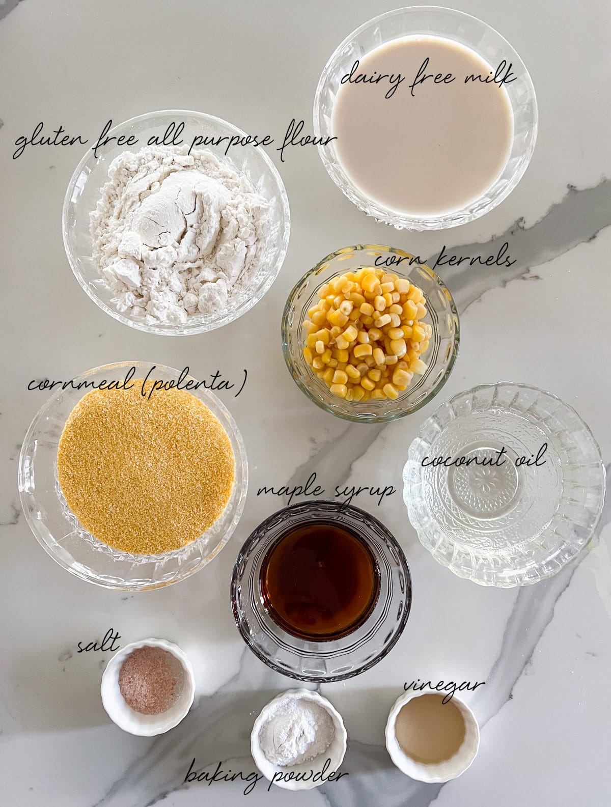 gluten free flour, dairy free milk, cornmeal, corn kernels, maple syrup, coconut oil, salt, baking powder and vinegar laid out in bowls