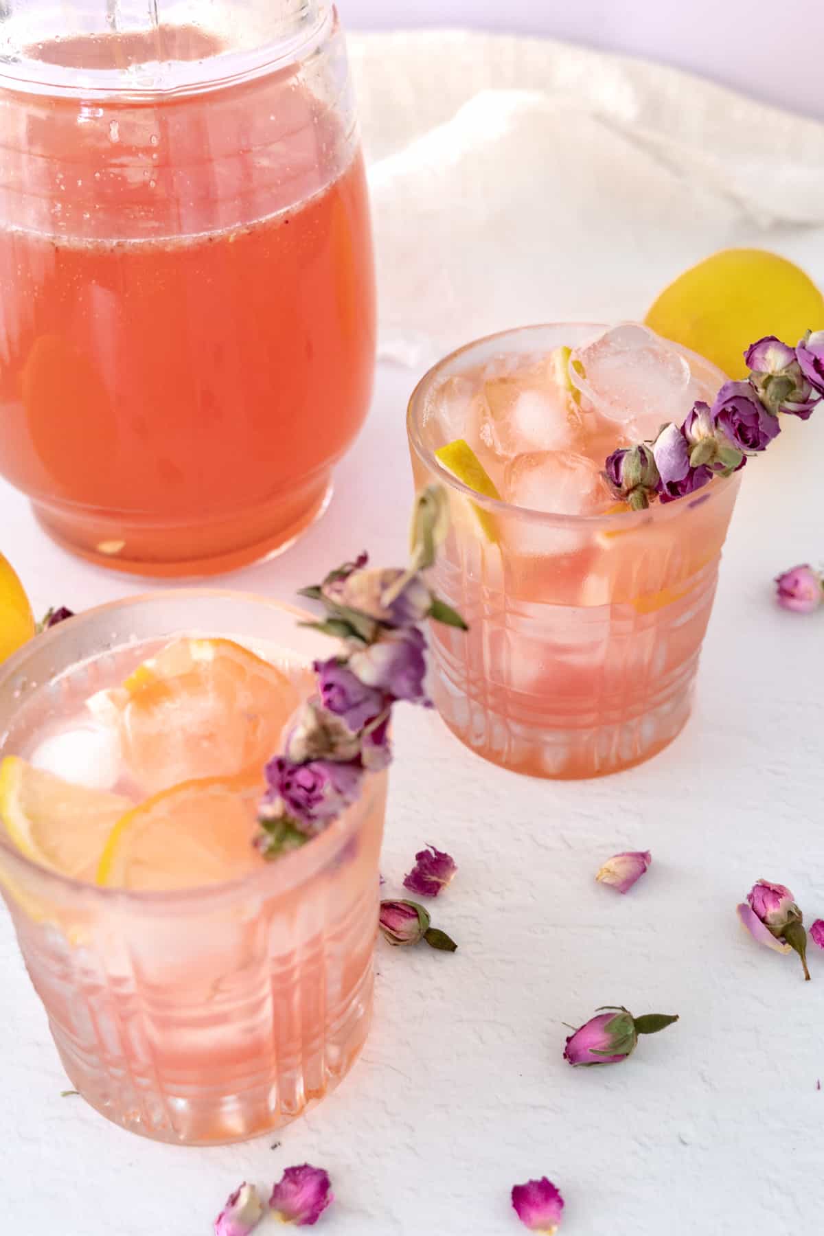 two serving glasses and a pitcher with pink lemonade