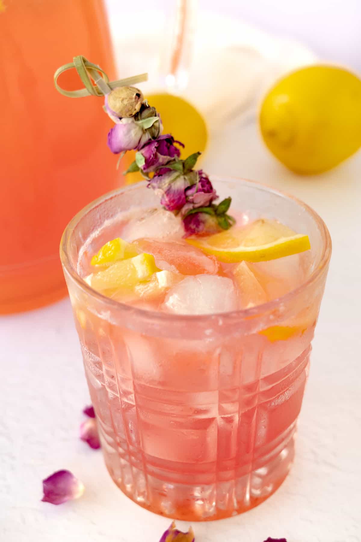 a glass of pink lemonade garnished with roses