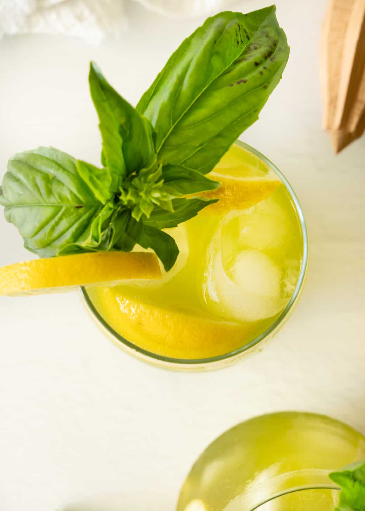 a birds eye view of glass cup filled with green basil  lemonade and fresh basil leaves