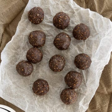 chocolate peanut butter balls laid out on parchment paper with a tea towel