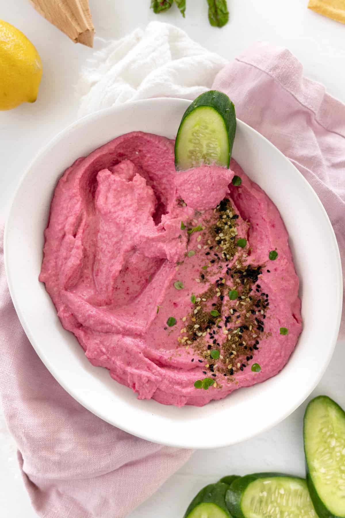 a piece of cucumber in a bowl of beetroot hummus