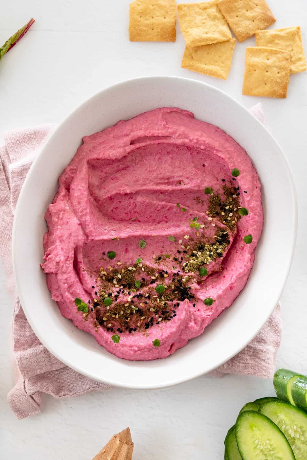 a white bowl with pink beetroot hummus in it