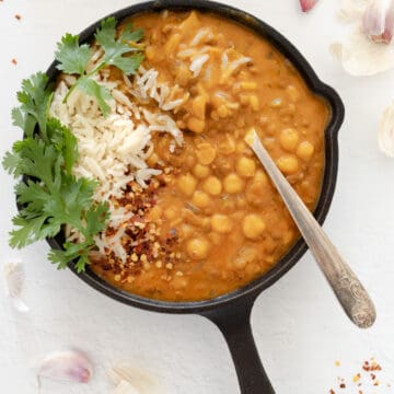 a cast iron pan with creamy chickpea and lentil curry and a side of rice