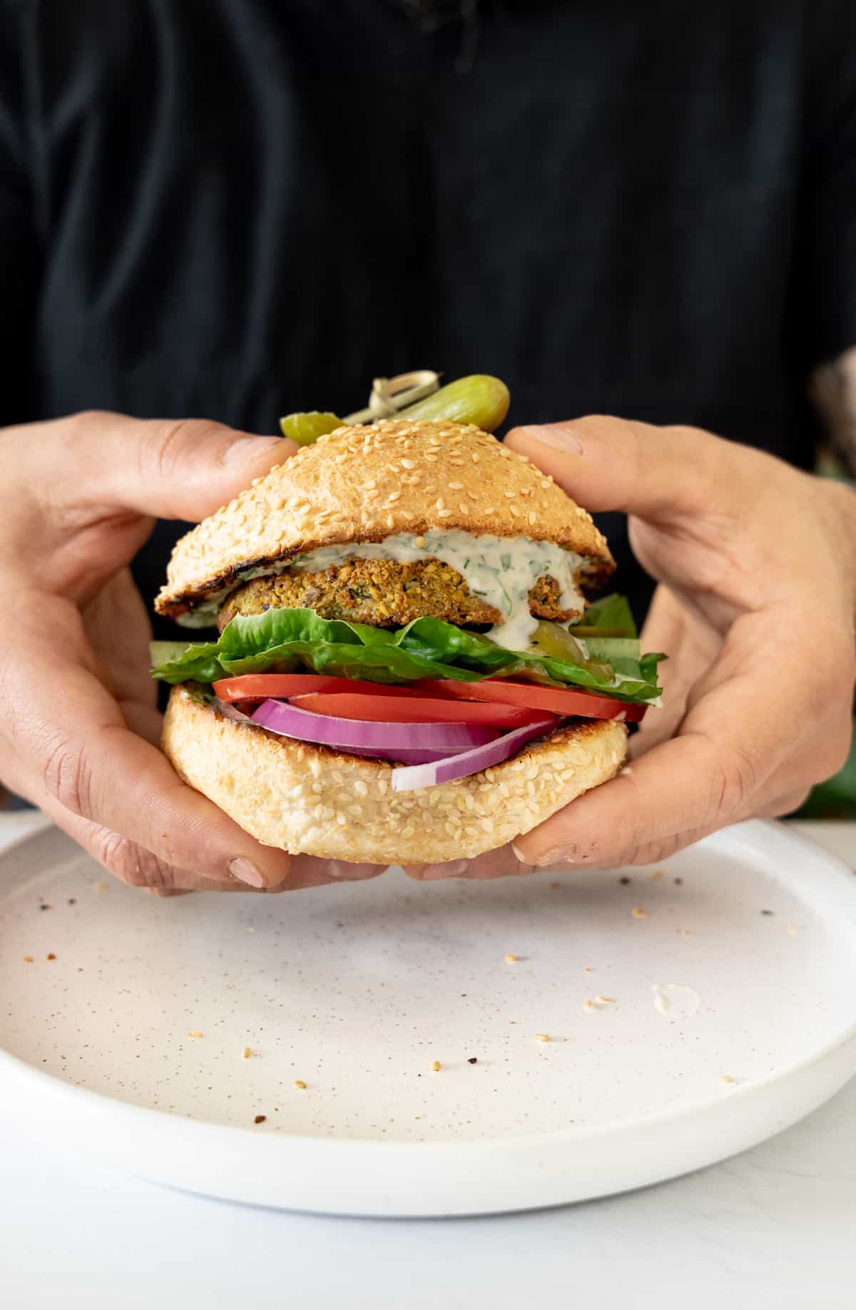 two male hands holding a falafel burger