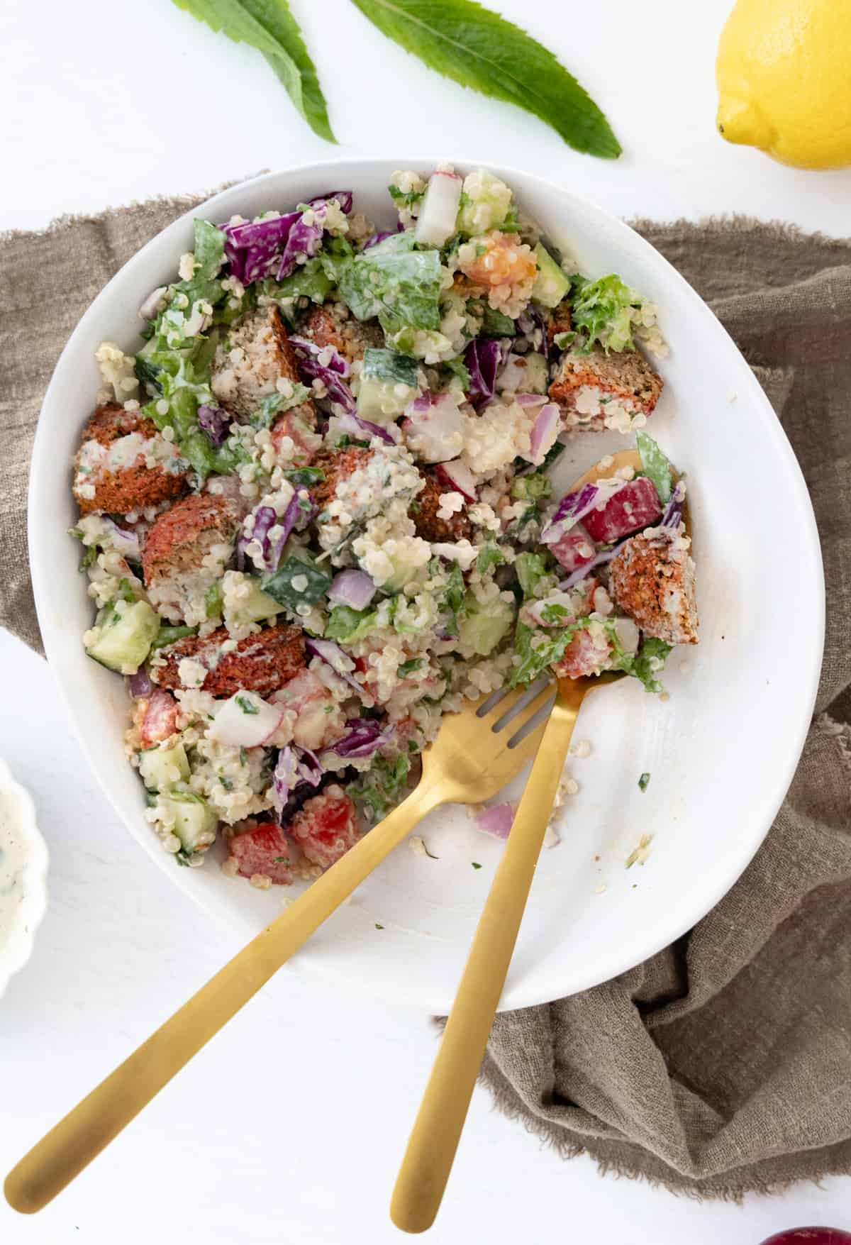 a falafel salad with lemon tahini dressing in a bowl with some of is eaten