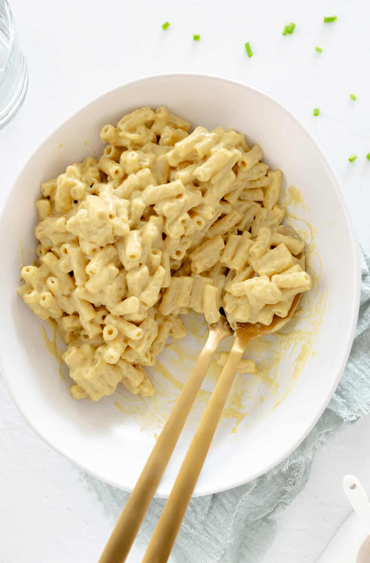 creamy macaroni pasta with vegan cheese sauce in a white plate with gold cutlery