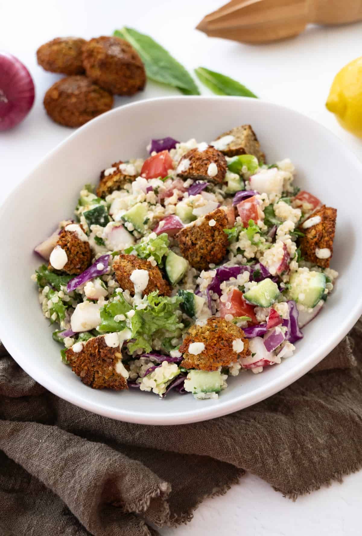 a bowlful of falafel salad with lemon tahini dressing drizzled on it