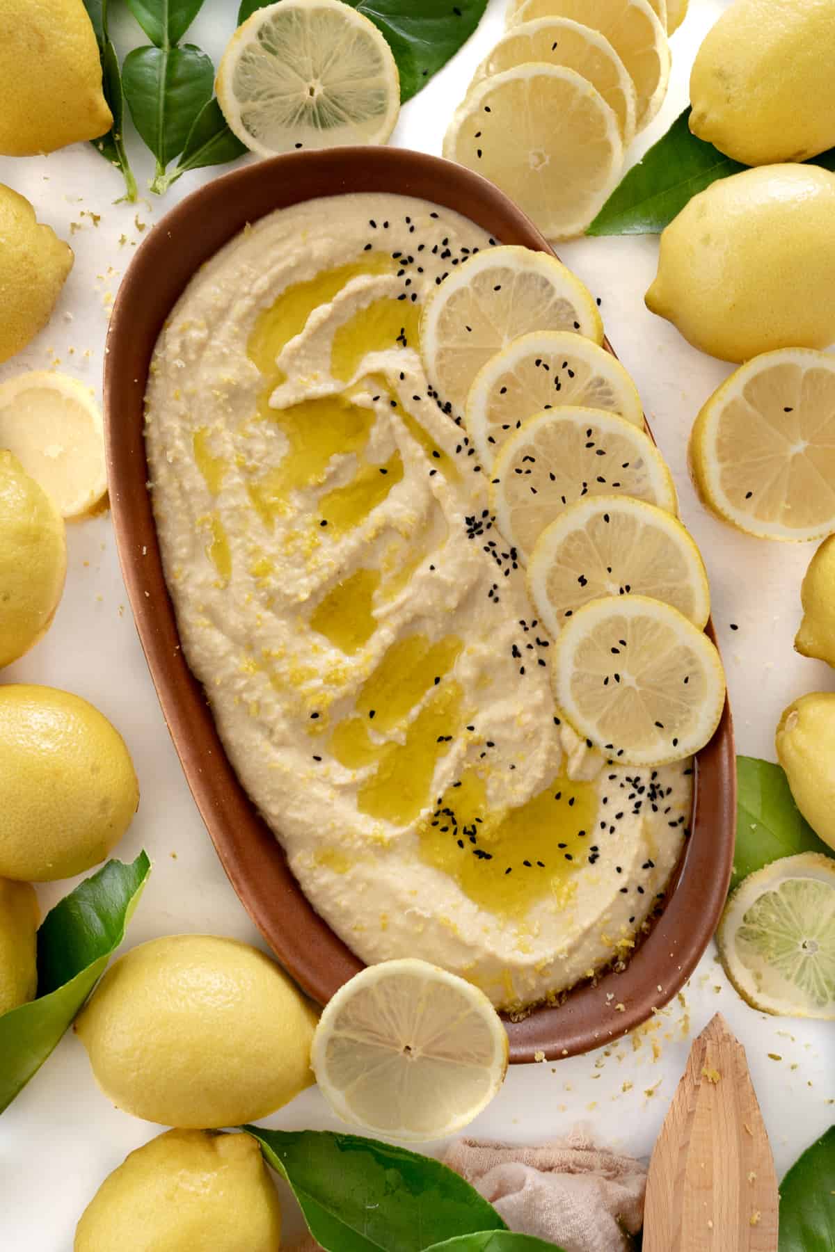 a plate of lemon hummus  wth black seeds surrounded by lemons