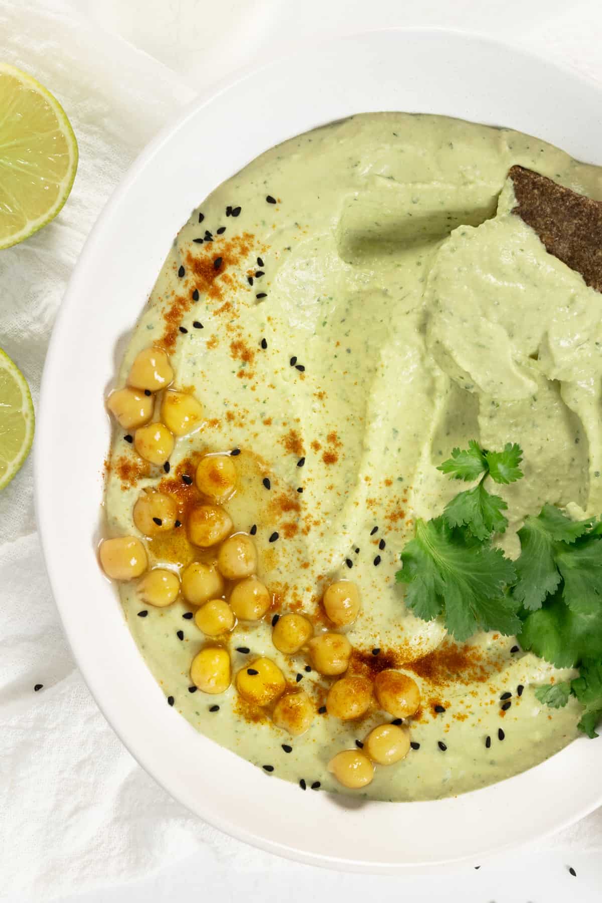 green lime cilantro hummus in a bowl with a cracker