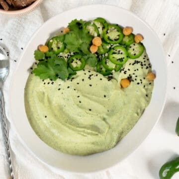 a white bowl of jalapeno cilantro hummus