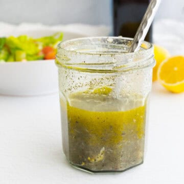 a glass jar of Lebanese salad dressing with a spoon in it