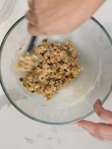 chocolate chip oatmeal cookie batter being folded in a glass bowl