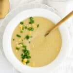 a white bowl of potato corn chowder with a spoon in it